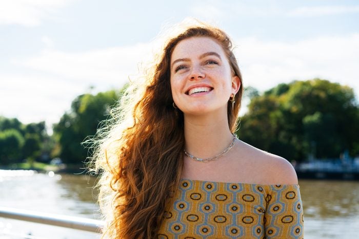 Woman smiling looking up next to river